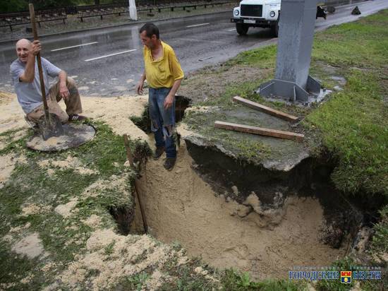 В Волгограде засыпают размытую дождем яму рядом с рекламным щитом